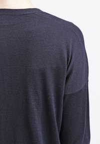 Mörkblå stickad tröja med en strukturerad yta, bred rund halsringning och sänkta axelsömmar som ger en avslappnad passform.