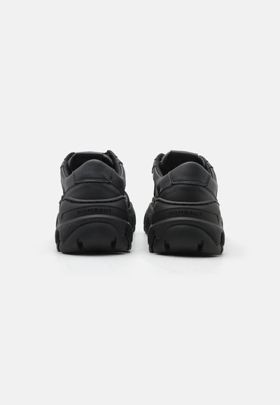 Schwarze Leder-Sneaker mit einer klobigen Sohle, die ein abgerundetes Fersendesign und geprägte Markenlogos auf der Rückseite aufweisen. Strukturelle Akzente verbessern die Griffigkeit.