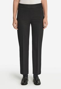 Svarta skräddarsydda byxor med platt midjeband, raka ben, tillverkade av slätt tyg, med minimal detaljer och rena linjer.