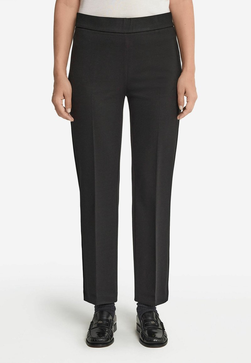 Svarta skräddarsydda byxor med platt midjeband, raka ben, tillverkade av slätt tyg, med minimal detaljer och rena linjer.