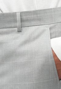 Calças texturizadas cinzentas claras com um padrão de xadrez subtil, apresentando um corte direito, bolsos laterais e uma cintura plana.