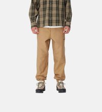 Mallas de felpa marrones con un corte ajustado, que cuentan con parches de rodilla reforzados y una waistband elástica. Combinadas con una camisa de cuadros con patrón.