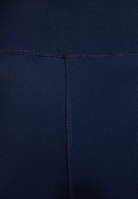 Navy wysokie legginsy z elastycznego materiału o gładkiej fakturze, z wzmocnionymi szwami dla zwiększenia trwałości.
