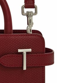 Borsa a mano in pelle rossa con texture, dotata di una chiusura in metallo argentato e un grande logo 'T' argentato sul davanti, completa di una tracolla coordinata.