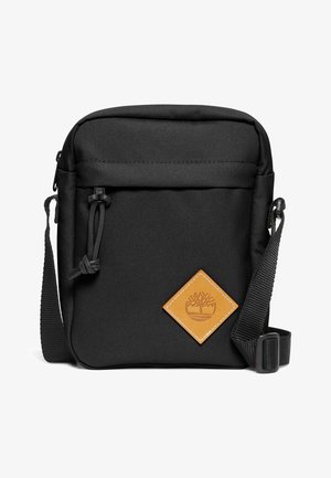 Borsa a tracolla nera in tessuto con superficie testurizzata, caratterizzata da una forma rettangolare, tracolla regolabile e un patch logo a forma di diamante marrone.
