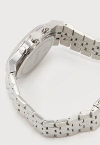 Ανδρικό ρολόι χειρός από ανοξείδωτο ατσάλι με μπρασελέ από μεταλλικούς κρίκους, τρία πλευρικά κουμπιά και χαραγμένο όνομα μάρκας στο κορώνα και στην πίσω όψη της κάσας.