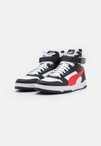 Sneaker alte in pelle nera, bianca e rossa con una finitura testurizzata. Presentano un marchio ben visibile e una fascetta regolabile attorno alla caviglia.