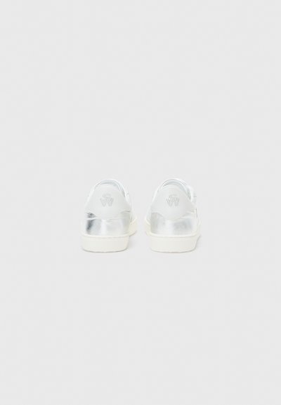 Metallic silver slip-on-skor med en vit sula och vadderad häl. Har präglad logotypdetalj på hälfliken. Slät textur.