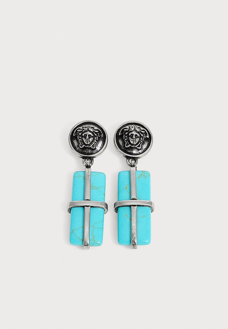 Boucles d'oreilles en argent avec des têtes rondes de Méduse et des pierres rectangulaires turquoise pendantes croisées par des barres en argent.