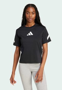 Svart kortärmad t-shirt i bomull med en vit Adidas-logotyp på bröstet och vita detaljer på ärmarna. Enkel design, rundad halsringning.