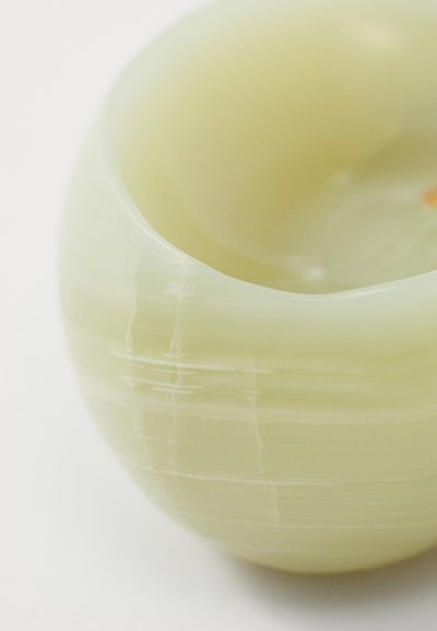 Translucent green bowl made of onyx with a smooth, curved shape. It features subtle white lines and a small red accent inside.