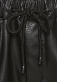 Sort faux læder shorts med en samlet talje og justerbar snor. Har en glat tekstur og sort snor med toggle-ender.