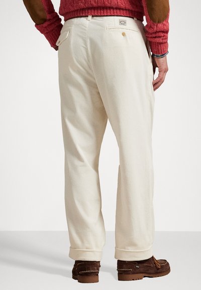 Pantalones de pana color crema con corte recto, que cuentan con bolsillos traseros, puños doblados y detalles de costura visibles.