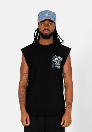 Zwarte mouwloze t-shirt met een grafisch ontwerp op de linkerborst, gemaakt van katoen. Draagt een blauwe met patroon bedekte pet. Minimalistische stijl.
