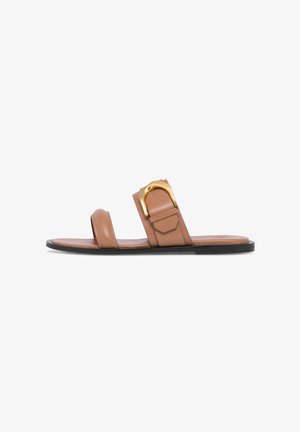 Brown flat slide sandal with two leather straps, one featuring a large gold buckle detail, and a black sole.