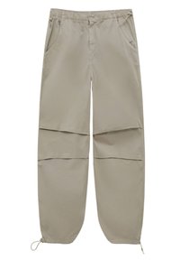 Pantalon cargo beige convertible avec taille élastique, poches latérales, jambes zippées amovibles et cordons réglables aux chevilles.