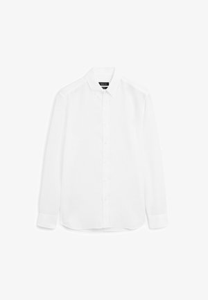 Hvid langærmet skjorte lavet af glat stof, med knaplukning foran, spidse kraver og rundet kant med knapmanchetter.