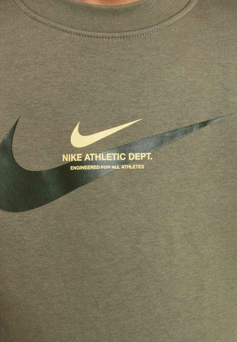 Oliwkowa bawełniana koszulka z okrągłym dekoltem, z czarnym logo Nike w kształcie ptaka i złotym napisem: "NIKE ATHLETIC DEPT., ENGINEERED FOR ALL ATHLETES."