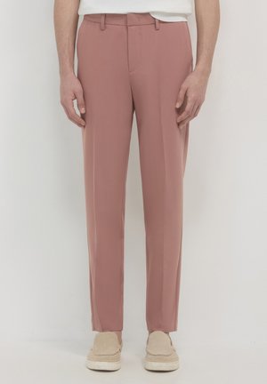 Maßgeschneiderte rosa Hosen aus glattem Stoff, mit einem flachen Vorderdesign, Seitentaschen und geradem Bein. Kombiniert mit beigen Loafers.