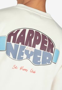 Biała bluza z nadrukiem w odważnych, wielokolorowych grafikach z napisem "HARPER AND NEYER" oraz "Ski Preppy Club" w różnych czcionkach i rozmiarach.