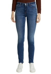 Smala jeans i blå denim med en urtvättad effekt vid låren, med fem fickor, kn äppning med knapp och använda med vita sneakers.