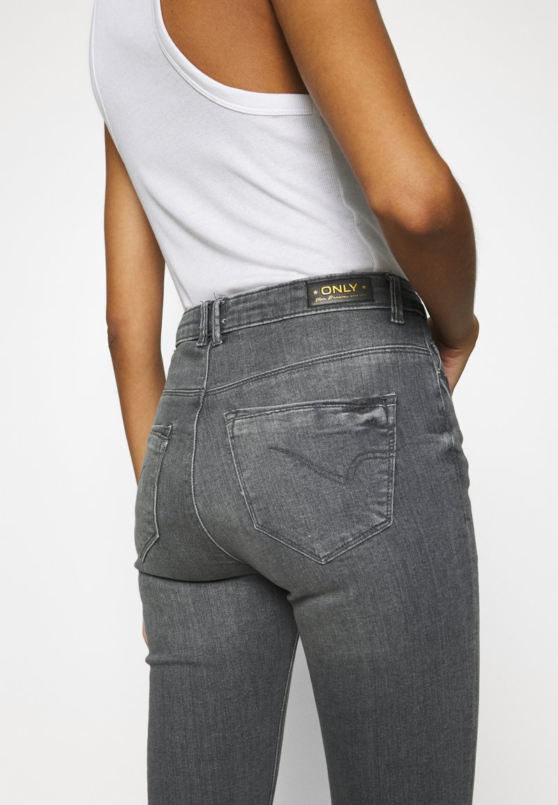Hochtaillierte graue Jeans mit leicht verblasstem Finish, ausgestattet mit einem schwarzen Markenetikett am Bund und dekorativen Nähten an den Gesäßtaschen.