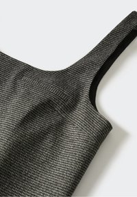 Tissu gris texturé avec un motif subtil, présentant un décolleté large et des bretelles étroites. L'intérieur est noir, apportant un contraste.