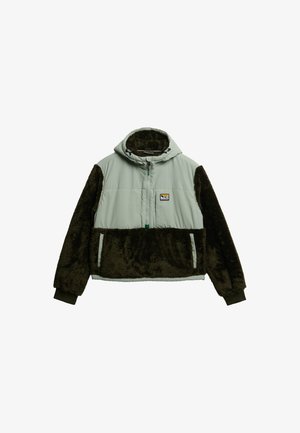 Gevoerde jas met een lichtgrijze bovenkant en donkere bruine nepbont ondermouwen en onderkant. Voorzien van een rits aan de voorkant en twee zijzakken.