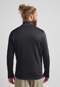 Schwarzer Langarmpullover mit hohem Kragen, aus einem strukturierten Stoff gefertigt. Verfügt über kontrastierende Schulterakzente und ein figurbetontes Design.