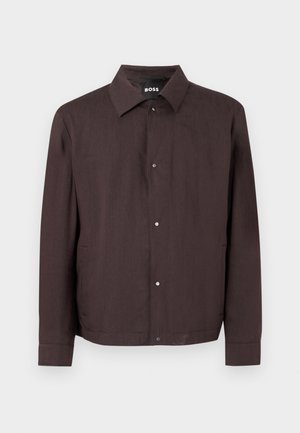 Dunkelbraune Freizeitjacke mit Kragen und vorderen Druckknöpfen, langen Ärmeln und Seitentaschen, präsentiert auf einfachem weißem Hintergrund.