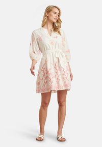 White dress with pink floral embroidery, V-neckline, 3/4 sleeves, cinched waist with a fabric tie, flowing above the knee.