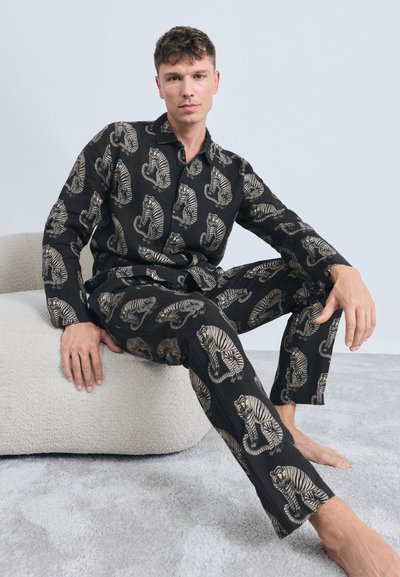 Black pajama set featuring a tiger pattern. The shirt has a collar and buttons, while the pants are loose-fitting with an elastic waistband.