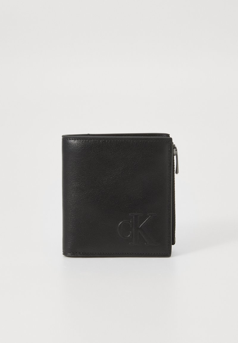 Zwarte leren portemonnee in vierkante vorm, met een ritssluiting en een reliëf "cK" logo aan de voorkant. Gladde textuur, minimalistisch ontwerp.