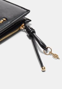 Czarny skórzany portfel z fakturowanym wykończeniem, wyposażony w zamek błyskawiczny w złotym odcieniu, ozdobny chwost i dekoracyjny brelok.