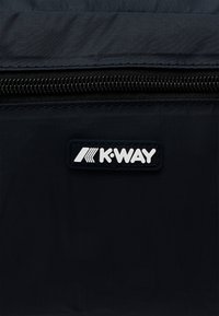 Crna najlonska torbica s glatkom teksturom, koja ima vidljiv crni patentni zatvarač i bijeli K-WAY logotip na zakrpi. Jednostavan pravokutni dizajn.