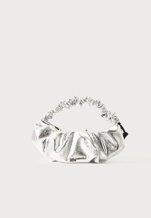 Kleine silberne Metallic-Handtasche mit geraffter Stofftextur und gerafftem Griff auf hellem Hintergrund.