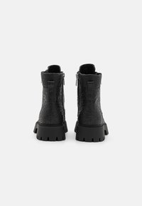 Bottines noires avec un design embossé texturé, dotées d'une semelle en caoutchouc épaisse et de zips latéraux pour un enfilage facile.