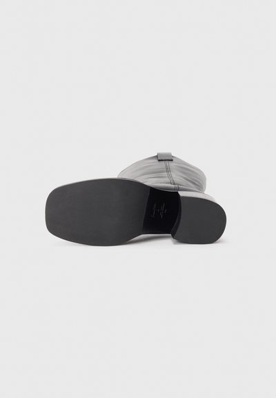 Gray leather shoe with a smooth surface, a rounded toe, and a flat black sole. Features a simple design and minimalistic accents.