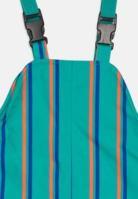 Teal fabric with vertical stripes in orange and blue. Features adjustable straps and a plastic buckle for secure fastening.