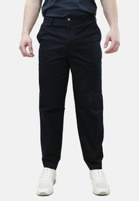 Pantaloni blu scuro in cotone misto. Taglio sartoriale, dotati di chiusura con zip e bottone. Indossati con sneakers bianche.