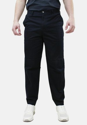 Pantaloni blu scuro in cotone misto. Taglio sartoriale, dotati di chiusura con zip e bottone. Indossati con sneakers bianche.