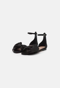 Sandali neri flat con dettaglio di un fiocco in satin annodato, cinturino alla caviglia, punta aperta e soletta testurizzata per una migliore aderenza.