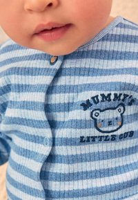 Striped blue baby cardigan made of soft fabric, featuring a cartoon bear graphic and text "MUMMY'S LITTLE CUB," with round buttons.