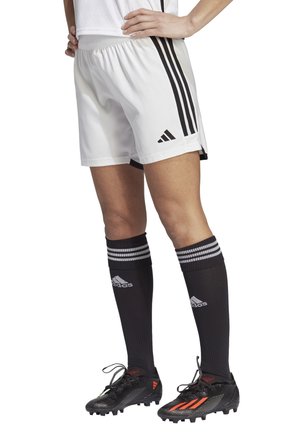 Witte sportshorts met een zwart drie-strepen ontwerp, gecombineerd met zwarte sokken met witte strepen en zwarte voetbalschoenen met rode accenten.