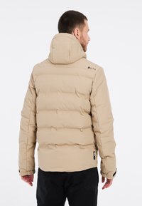 Veste rembourrée beige avec capuche, dotée d'un design matelassé et de poignets élastiques. Logo sur l'épaule. Texture lisse et matériau résistant à l'eau.