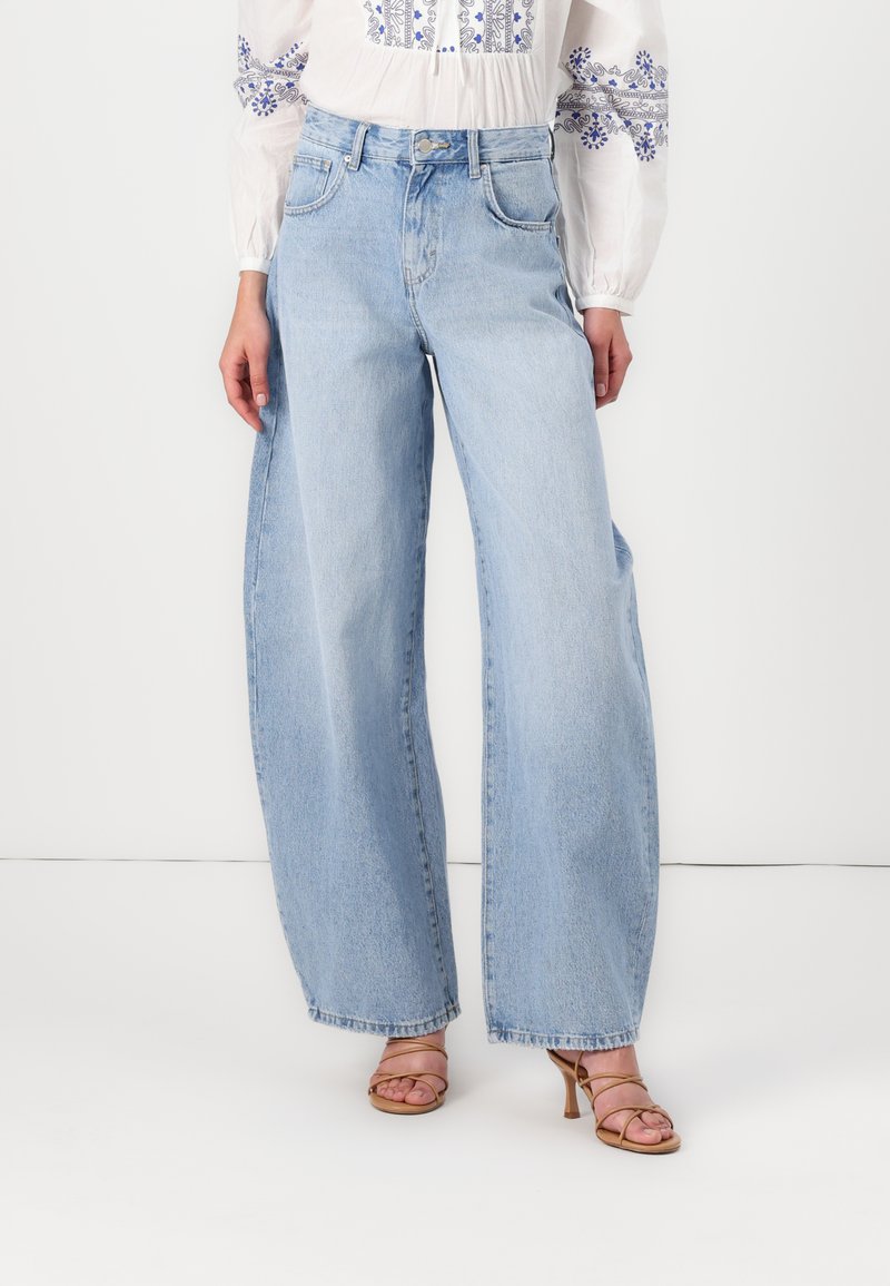 Jeans a gamba larga di colore blu chiaro con vita alta, realizzati in denim. Presentano un classico design a cinque tasche e una leggera texture sbiadita.
