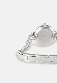 Silberne Armbanduhr aus rostfreiem Stahl mit rundem Gehäuse, Gliederarmband und einer glatten polierten Oberfläche. Sichtbares Branding auf der Schließe.