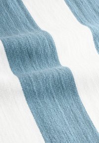 Textil rayat cu secțiuni alternative de albastru deschis și alb, având o suprafață texturată și un tipar de țesătură.
