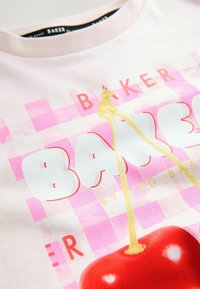 Růžovo-bílý kostkovaný vzor s velkými bílými písmeny, červeným textem "BAKER" a velkou červenou třešní se žlutým stonkem na textilu.