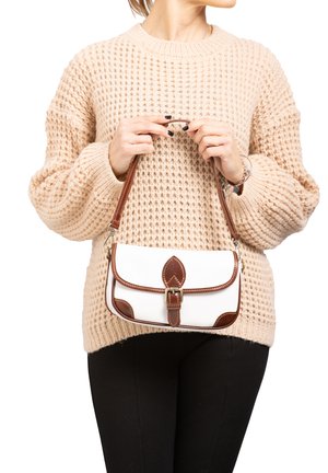 Weißes Lederhandtasche mit braunen Akzenten, ausgestattet mit einer dekorativen Schnalle und einem ovalen Deckel. Getragen von einer Person in einem strukturierten beigen Pullover.
